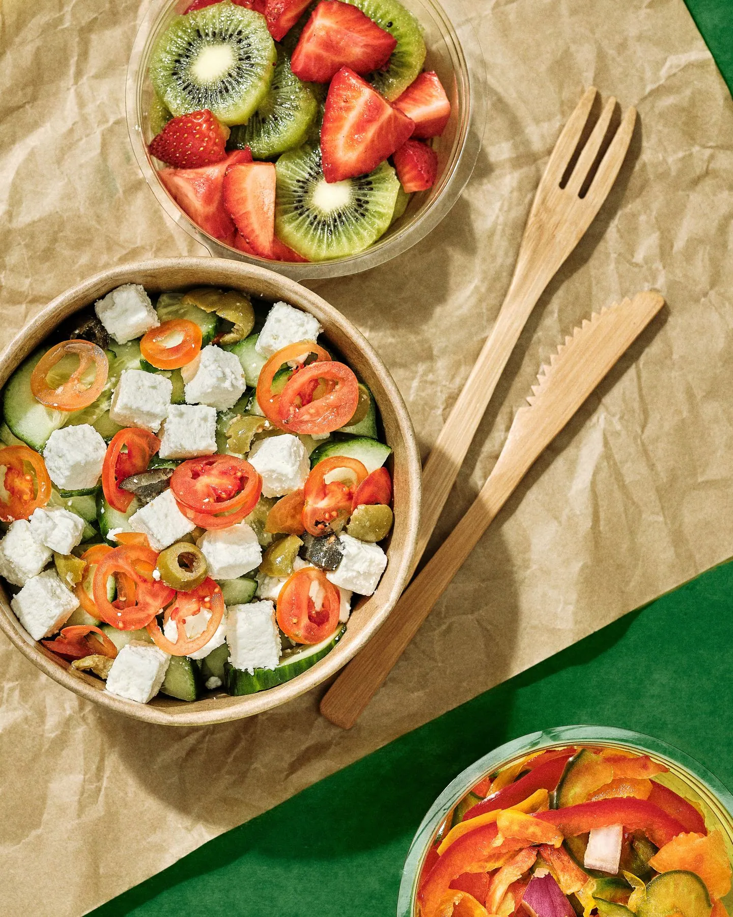 Salade grecque et salade de fruits en bols kraft, couverts en bois