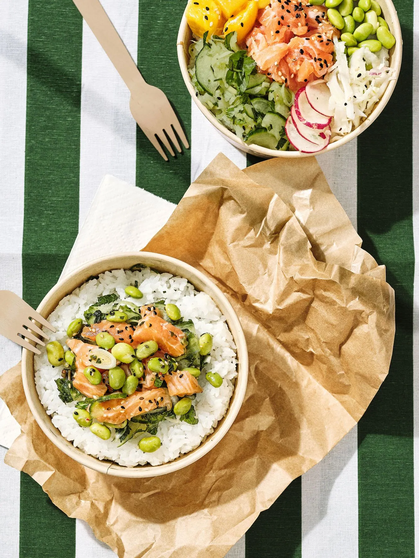 Poke bowls au saumon, edamame et crudités sur une nappe rayée verte et blanche